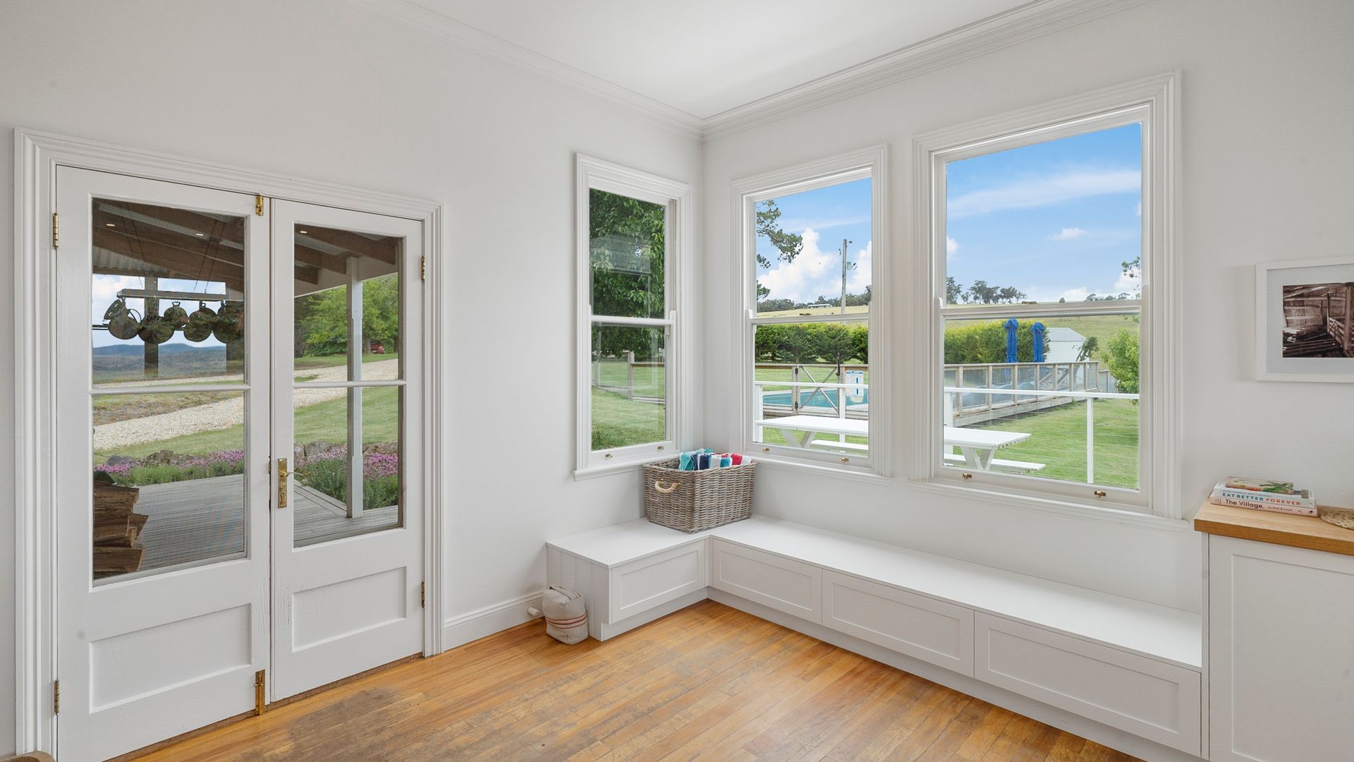 A room with a built-in bench along a large window overlooking a garden.
