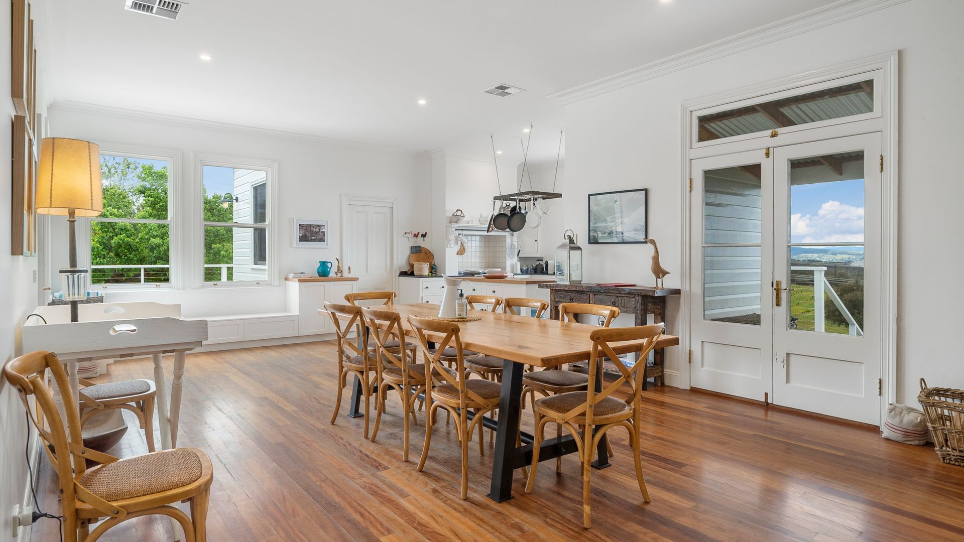 A spacious kitchen with a dining area, white cabinetry, and a view through a glass door.