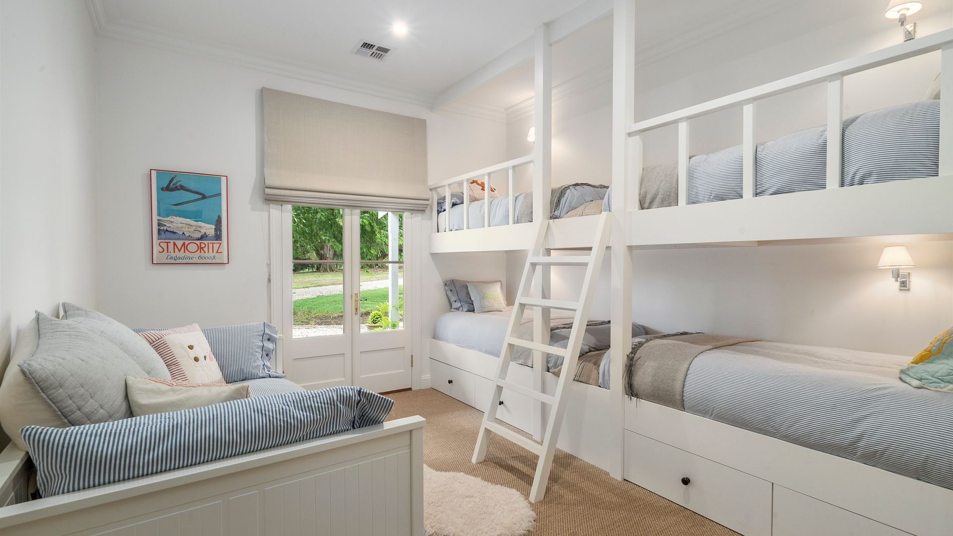 A child's bedroom with bunk beds, a ladder, a window with a view, and a poster on the wall.