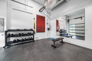 Ein Fitnessraum mit einer Bank, Kurzhanteln und einem Spiegel.