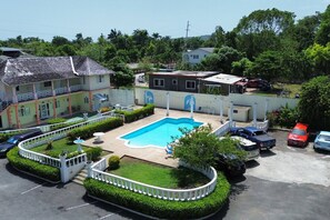A residential property with a swimming pool, a fenced garden, and a parking area with several cars. - Modern Refurbed Condo | Resort Pool | Sleeps 4 (Ocho Rios)