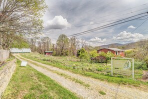 Ländliche Landschaft mit einem Kiesweg, einem Gewächshaus und einem roten Gebäude.