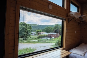 Ein Holzblockhaus-Interieur mit einem großen Fenster mit Blick auf eine ländliche Landschaft.