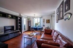 Ein modernes Wohnzimmer mit einer Ledersofa, einem Fernseher und einem Essbereich mit Tisch und Stühlen.