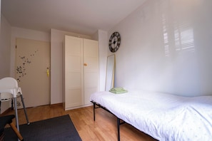 Ein Schlafzimmer mit Bett, Stuhl, Kleiderschrank und Spiegel.