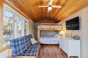 L'intérieur d'une cabine comprenant un lit superposé, un canapé, un téléviseur et un plafond en bois.