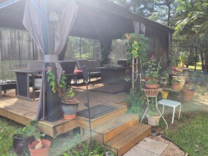 A covered outdoor seating area with a table and chairs, surrounded by potted plants and a wooden deck. - Spacious 4BR house tranquil lakeview w boat launch beach access/park extra prkng (Jacksonville)