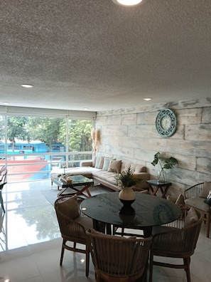 A modern living room with a stone wall, a round table, and a sofa. - Beautiful New Apartment in Downtown Coyoacán (Ciudad de México)