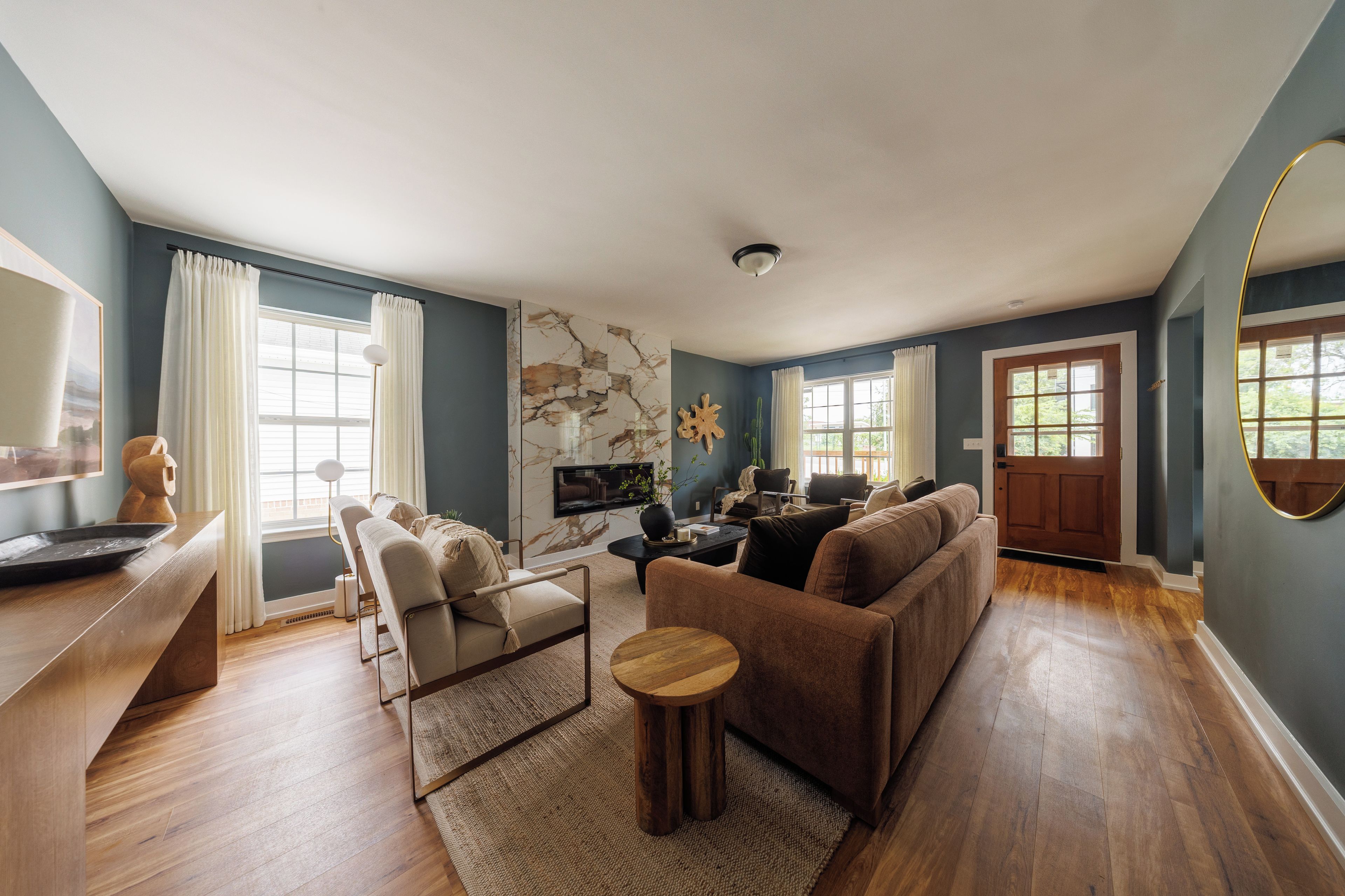 A spacious living room with a large sofa, a coffee table, and a flat-screen TV mounted on the wall.