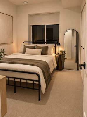 Een slaapkamer met een bed, nachtkastje, lamp en spiegel.