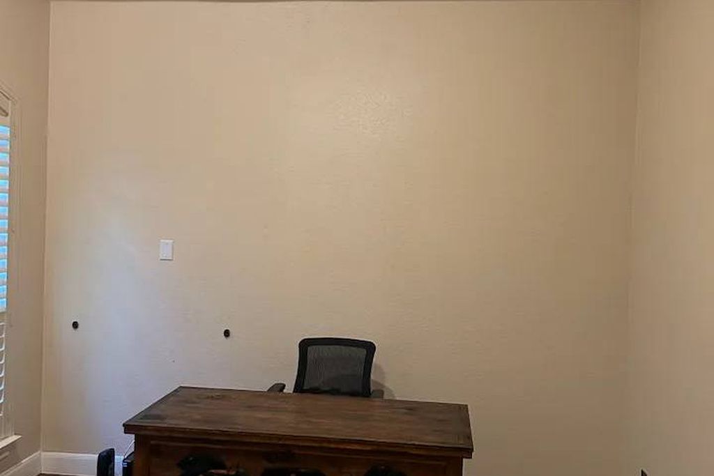 A room with a wooden table and a single black chair.