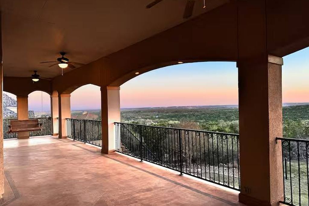 A covered balcony with a view of a landscape.