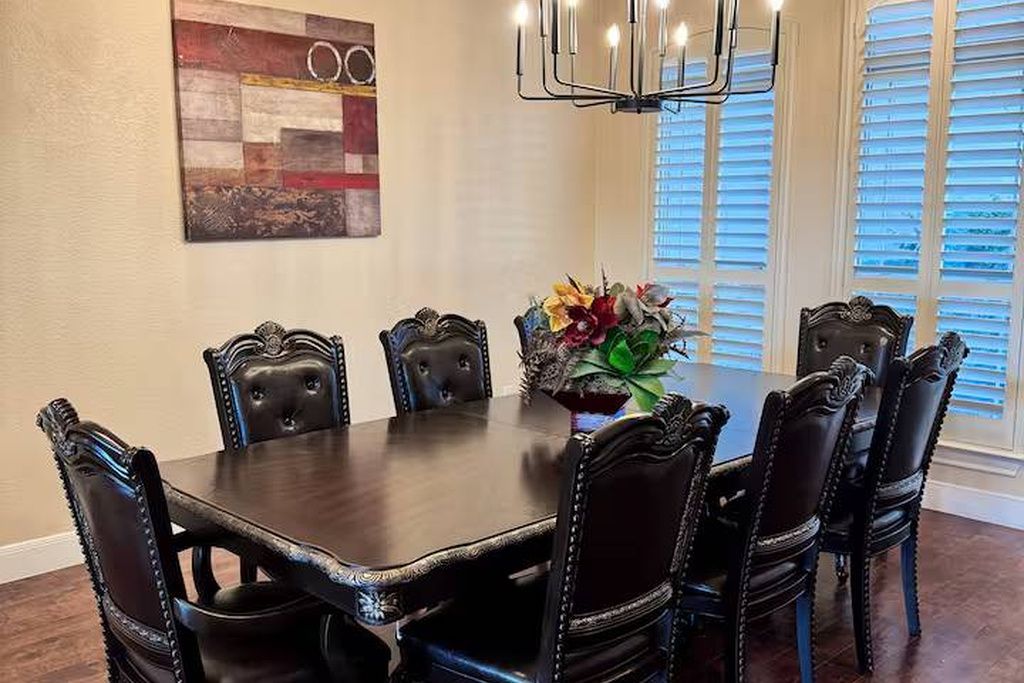 A dining room with a dark wooden table surrounded by six upholstered chairs with decorative elements.