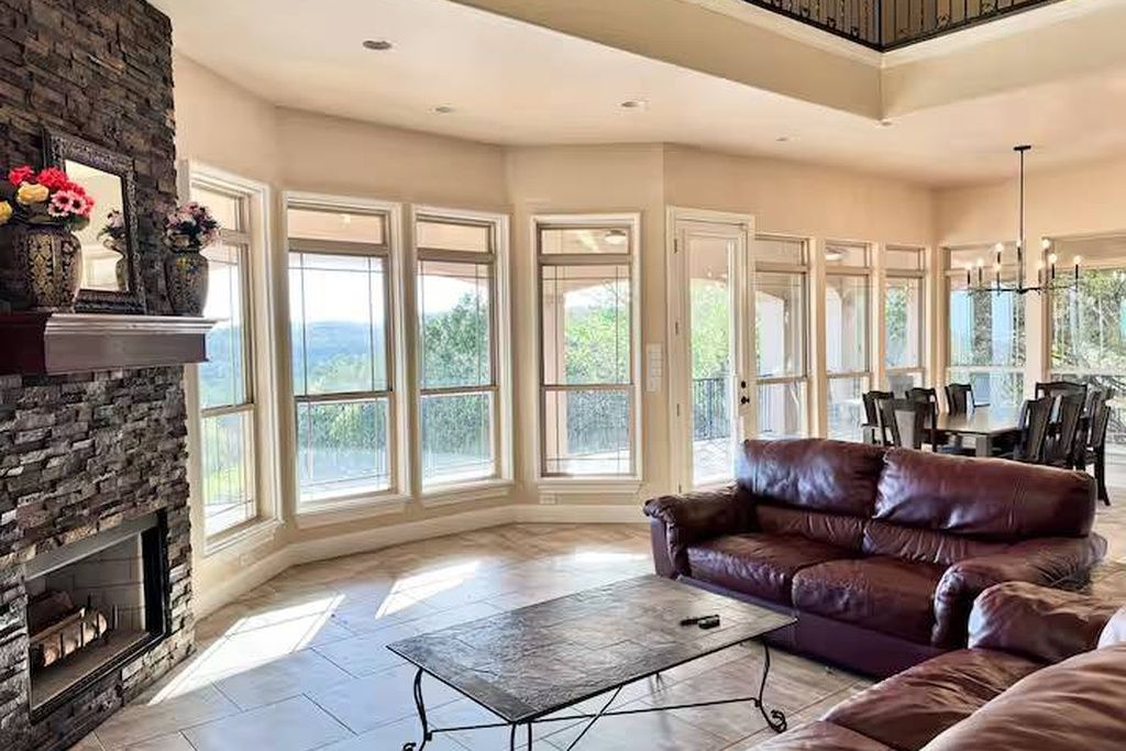 A spacious living room with a fireplace, large windows, and a leather sofa.