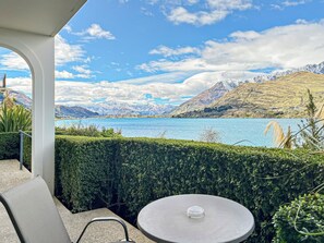 A terrace with a table and chairs overlooking a lake with mountains in the background. - Newly Renovated Lakefront Retreat, Sleeps 2 (Queenstown)