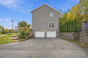A two-story house with a garage, a stone wall, and a well-maintained lawn. - Hudson Landing - Fireplace & Catskills Retreat (Saugerties)