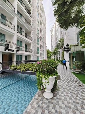 Ein Hotelinnenhof mit Swimmingpool, Topfpflanzen und einer Person, die gerade geht.