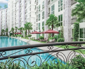 A hotel with a swimming pool, sun loungers, and palm trees. - City Olympus Garden Condominium - 1 luxury bedroom - 5 swimming pools in Pattaya (Muang Pattaya)