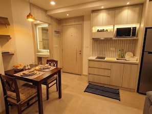 A modern kitchen with wooden cabinets, a microwave, and a refrigerator. - City Olympus Garden Condominium - 1 luxury bedroom - 5 swimming pools in Pattaya (Muang Pattaya)