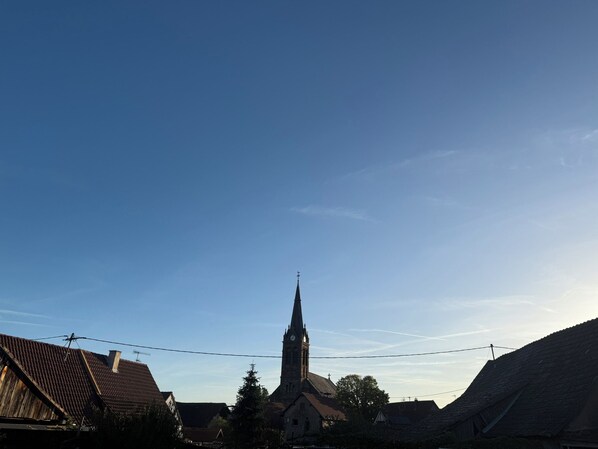 Een kerk met een hoge spits en een klokkentoren, omringd door woongebouwen met schuine daken.