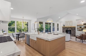 A modern kitchen with a large island, pendant lighting, and a stone fireplace. - NEW Saugatuck sleeps 12_Pool_Hot Tub_Game Room (Hamilton)