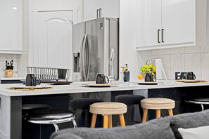 A modern kitchen with a stainless steel refrigerator, a sink, and bar stools. - Stylish 3bed 2.5bath//2Mins Stadium//RAH// Rogers//DT//Fast Wi-Fi Free Parking (Edmonton)