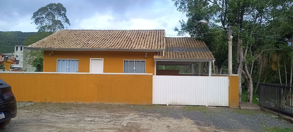 A two-story building with a tiled roof and a white fence in front.