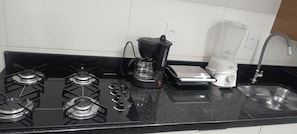 A kitchen with a black stove, a coffee maker, and a blender.