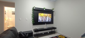 A living room with a flat-screen TV mounted on the wall, a black entertainment unit below, and a black sofa.