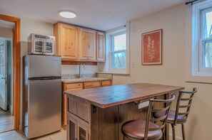 Eine Küche mit Holzausstattung, einem Edelstahlkühlschrank, einer Granitarbeitsplatte und einer Holzinsel mit Stühlen.