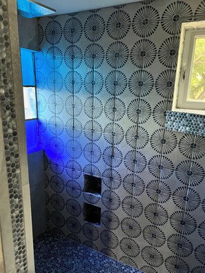 Ein Badezimmer mit einem Wandmuster, einem Fenster und einer blauen Leuchte.