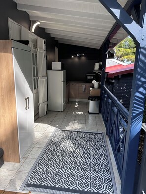 A narrow kitchen with white cabinets, a refrigerator, and a microwave. - Bungalow with a private pool and spa, just a 4-minute walk from the beach (Deshaies)