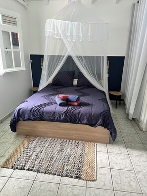 A bed with a canopy, a woven rug, and a small round table beside it. - Bungalow with a private pool and spa, just a 4-minute walk from the beach (Deshaies)