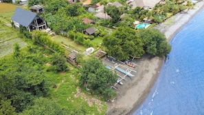 Vista aérea de una propiedad costera con piscina, barcos y exuberante vegetación.