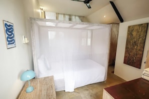 Una camera da letto con un letto a baldacchino, un comodino con una lampada e opere d'arte alle pareti.
