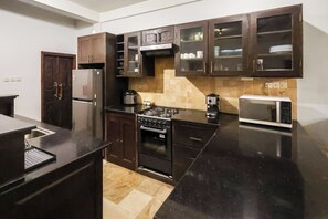 Una cucina moderna con mobili scuri, piano cottura a gas, forno a microonde e forno integrato.