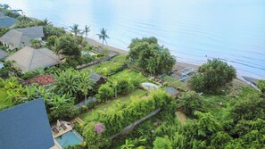 Zona residenziale con piscina, vegetazione lussureggiante e spiaggia sullo sfondo.