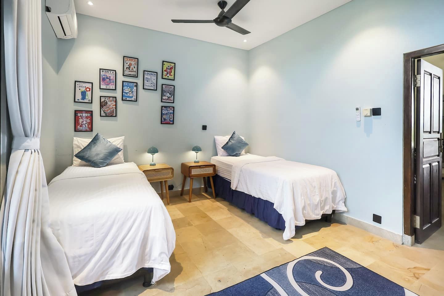 A bedroom with two beds, a ceiling fan, and a wall adorned with framed pictures.