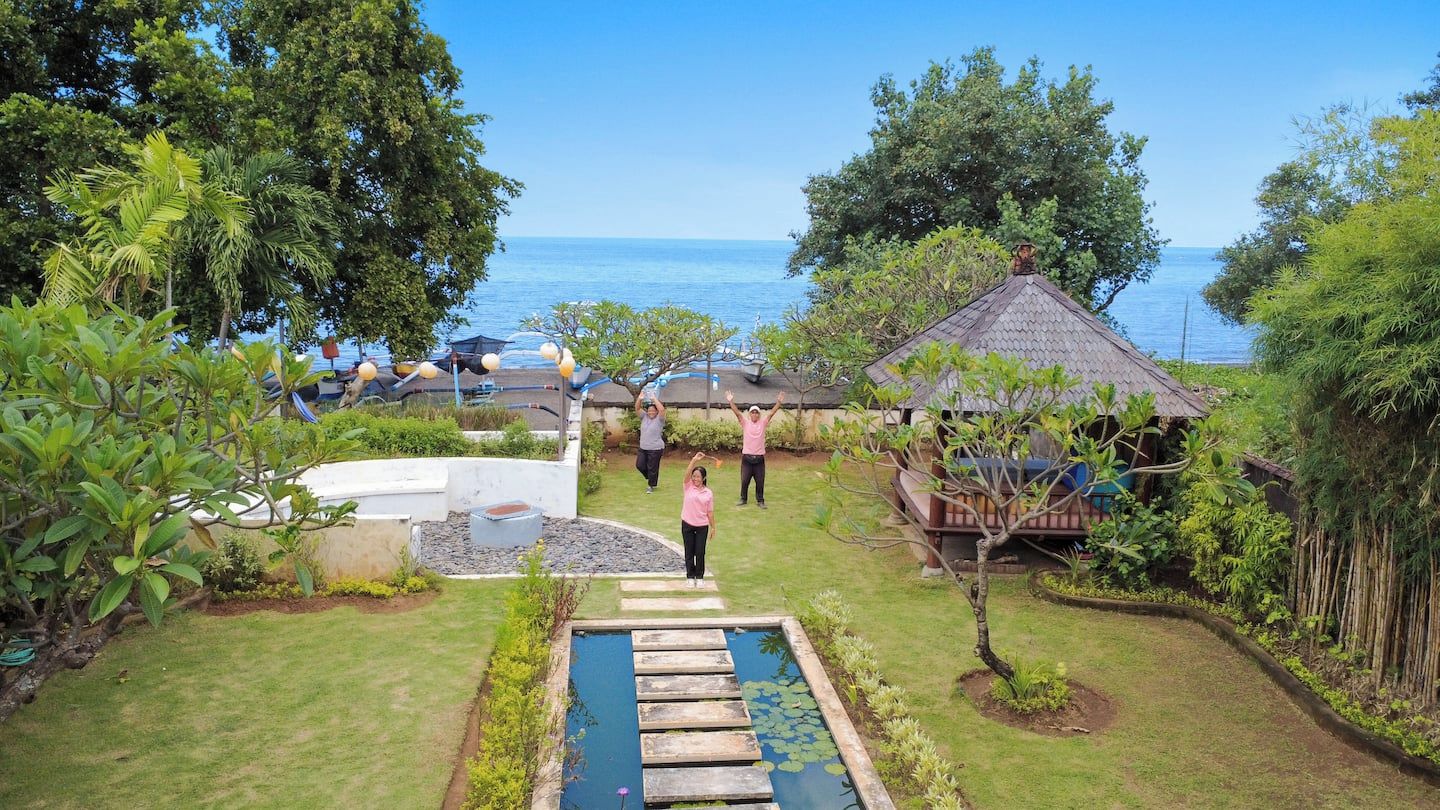 A pool with stepping stones, surrounded by lush greenery and a view of the sea.