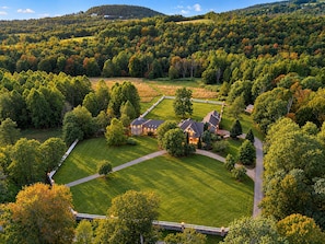 A large estate with multiple buildings, expansive lawns, and a surrounding forested area.