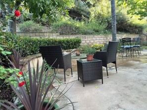 Un patio al aire libre con mobiliario de mimbre, una planta en maceta y un muro de ladrillo.
