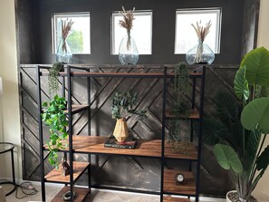 A wooden shelving unit with plants and a book titled 'World Atlas' against a dark wall with windows. - Elegant 4-bedroom 2,5 bath furnished & renovated house in beautiful Newbury Park (Thousand Oaks)