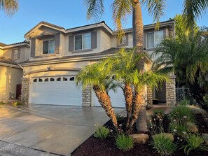 A residential house with a garage, palm trees, and a well-maintained garden. - Elegant 4-bedroom 2,5 bath furnished & renovated house in beautiful Newbury Park (Thousand Oaks)