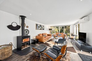 A modern living room with a fireplace, leather sofa, and a television. - Links & Leisure Retreat - Relaxed Coastal Stay (Anglesea)