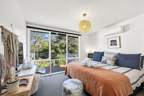 A modern bedroom with a large window, a bed with a brown blanket, a desk with a chair, and a macrame wall hanging. - Links & Leisure Retreat - Relaxed Coastal Stay (Anglesea)