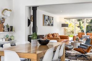 A modern living room with a dining area, featuring a wooden table, white chairs, a black bowl, and a potted plant. - Links & Leisure Retreat - Relaxed Coastal Stay (Anglesea)