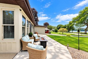 Ein Wohnhaus mit Terrasse, Gartenmöbeln und Seeblick.