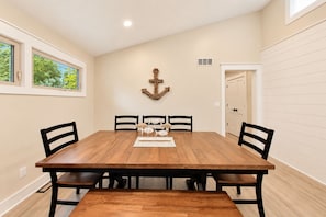 A dining room with a wooden table, four chairs, and a decorative anchor on the wall. - Pink Skies Landing | Steps to Powers Lake Beach (Genoa City)