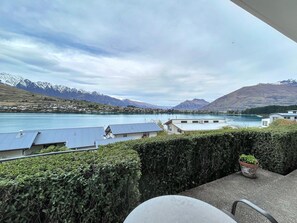 A balcony with a view of a lake and mountains, a chair, and a potted plant. - Cosy Alpine Lakeview Suite for Couples (Queenstown)
