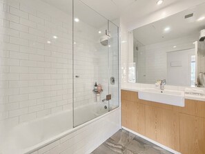 A modern bathroom with a glass-enclosed shower, white subway tiles, and a wooden vanity with a mirror. - Cosy Alpine Lakeview Suite for Couples (Queenstown)